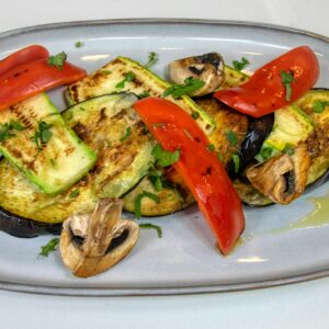 Delicious grilled vegetables with eggplant, zucchini, and red peppers on a plate.