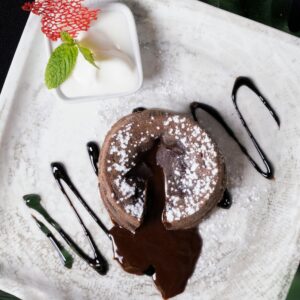 Delicious molten chocolate cake with powdered sugar and mint served on a plate.