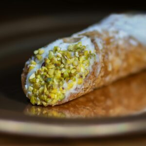 Close-up of a pistachio-topped cannoli pastry, showcasing the texture and vibrant colors.