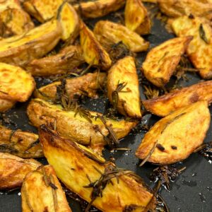 Freshly roasted potato wedges seasoned with rosemary, creating a golden crispy texture, perfect for food photography.